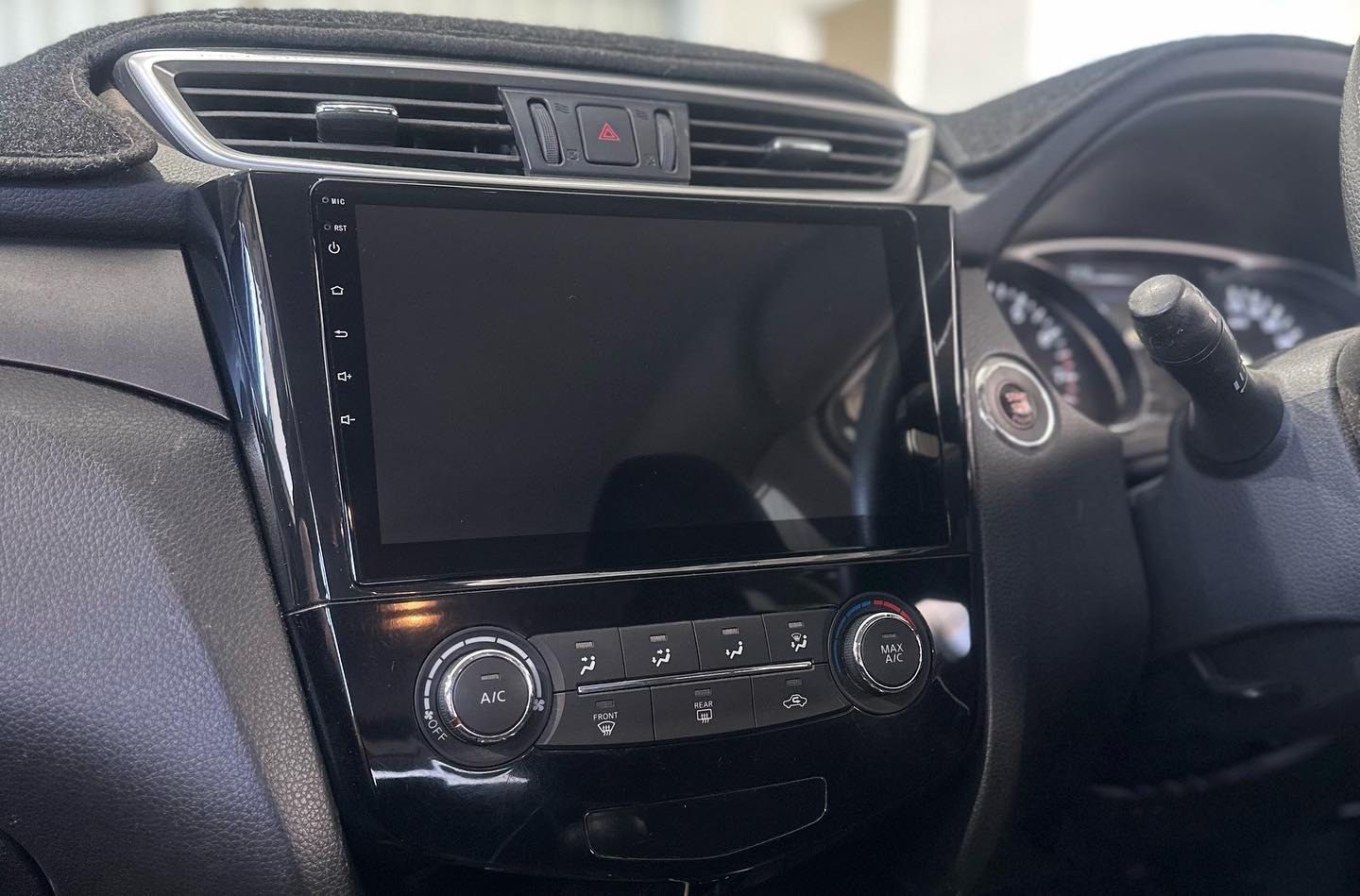 Aftermarket head unit fitted into a Nissan dashboard, screen off